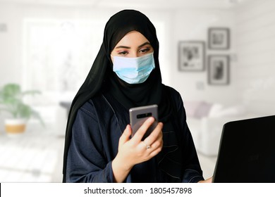 Female Arab wearing face mask while working from home. Arabic woman works remotely, keeping herself safe against pandemic virus outbreak COVID19