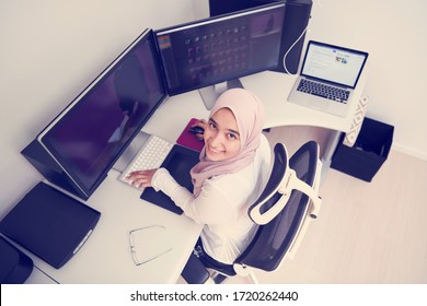 female Arabic creative professional  working at home office on desktop computer with dual screen monitor top view