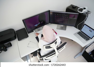 female Arabic creative professional  working at home office on desktop computer with dual screen monitor top view