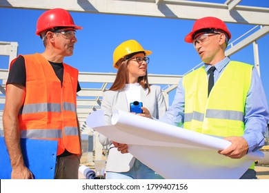 Female architect, construction engineer and manager talking about the project on construction site. Teamwork - group of builders and architect in hardhats, positive emotions, joy and smiles