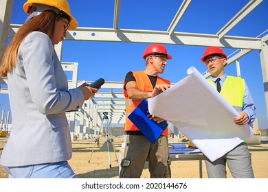 Female architect, construction engineer and manager talking about the project on construction site. Teamwork and people concept - group of builders and architect in hardhats