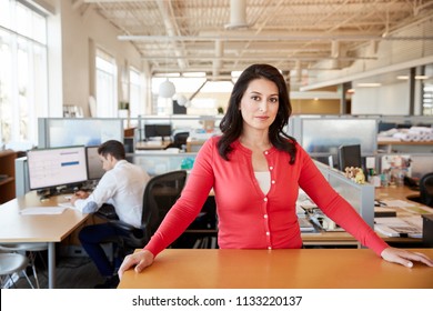 Female architect at a desk in an office smiling to camera - Shutterstock ID 1133220137