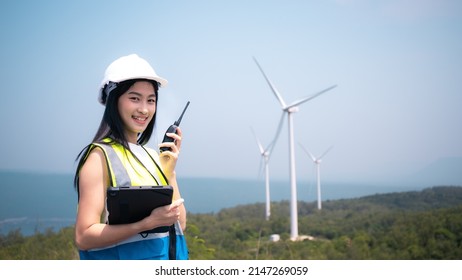 Female Architect Engineer Or Businessman Wear Hardhat Survey Wind Turbine Power Generator Field Site Project With Smart Tablet Device  Ecology Or Power Alternative Innovation Technology.Asian Worker.