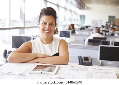 Female Architect At Her Desk, Smiling To Camera