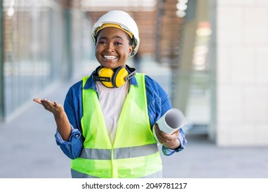 A female architect posing and looking at camera. Portrait of architect standing at building site and looking at camera with copy space. Female construction engineer. 