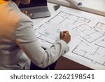 Female architect sitting at her office desk and working with blueprints, cadastral maps and city plans. Young African American woman studying information and developing a new architectural project