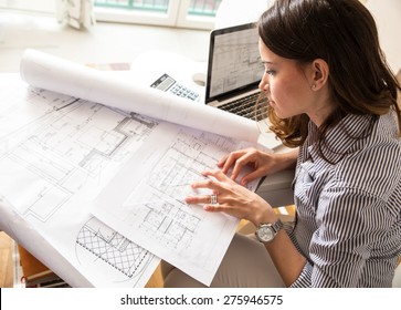 Female Architect Working At Home.She Looking Blueprints.