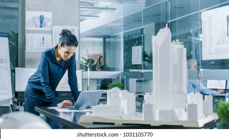 Female Architectural Designer Works on a Laptop,  Engineering New Building Model for the Urban Planning Project. Clean Minimalistic Office, Concrete Walls Covered by Blueprints and Documents. - Powered by Shutterstock