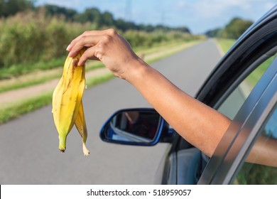 Female arm throwing  fruit waste out of car window