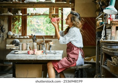 Female artist decorating and painting handmade ceramic clay cup at her creative workshop. Artwork and handmade concept - Powered by Shutterstock