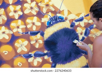 female artist hand with brush paints a street art bumblebee sunflower blossom mural, silicate paint, copy space - Powered by Shutterstock