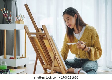 Female artist painting on canvas at home. Hobby and leisure concept.