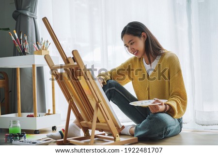 Female artist painting on canvas at home. Hobby and leisure concept.