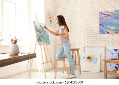 Female Artist Painting Picture In Workshop