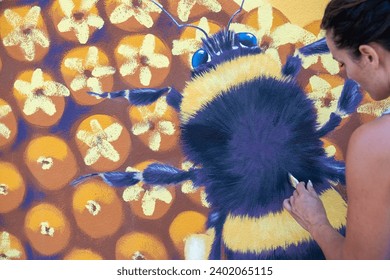 female artist woman paints with brush a street art bumblebee sunflower blossom mural, silicate paint, in Wuppertal Oberbarmen, copy space - Powered by Shutterstock