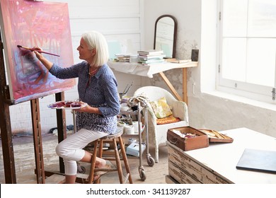 Female Artist Working On Painting In Studio