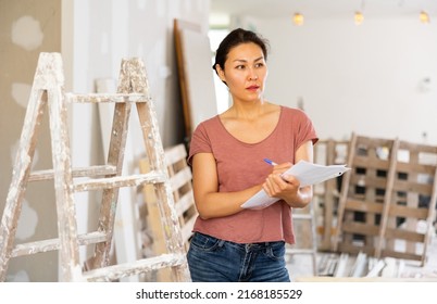 Female Asian Architect Matching Check List During Repair Works In House.