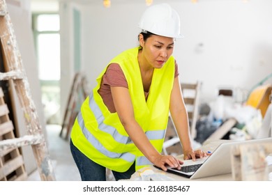 Female Asian Architect Using Laptop During Repair Works In House.