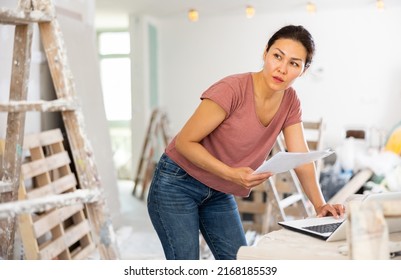 Female Asian Architect Using Laptop During Repair Works In House.