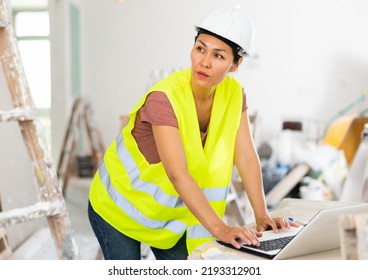 Female Asian Architect Using Laptop During Repair Works In House.