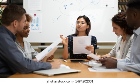Female asian boss executive holding paper talking negotiating with diverse partners clients presenting project plan to employees group discuss paperwork strategy at meeting table corporate briefing