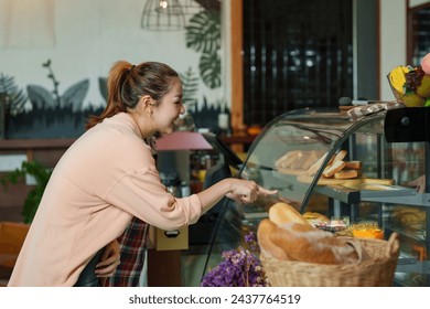 Female Asian customer standing selecting bakery goods and bread. Attentively Asian pensioner women. owns cafe and small businesswoman family business created an Asian tea daughter. - Powered by Shutterstock