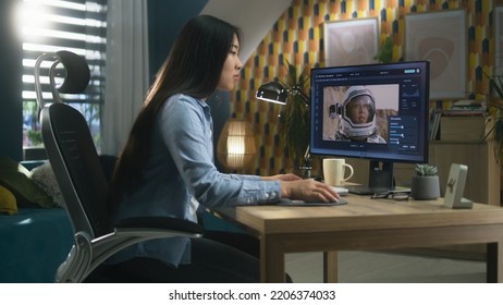 Female Asian Freelancer Editing Picture With Astronaut On Computer In Photoshop While Working Remotely From Home Office