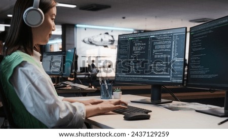 Female Asian Game Programmer Coding On Desktop Computer In Game Development Studio Diverse Office. Focused Woman Writes Lines Of Code. Gameplay Engineer of New Immersive 3D Survival Video Game Working