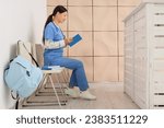 Female Asian medical intern reading book in clinic