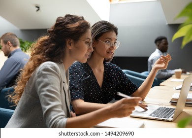 Female asian mentor teacher instructor teaching caucasian businesswoman help intern explaining online project instructing new worker trainee looking at laptop computer write notes sit at office desk - Shutterstock ID 1494209690