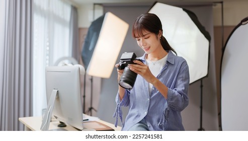 Female Asian photographer reviewing photo with camera shows satisfaction - Powered by Shutterstock