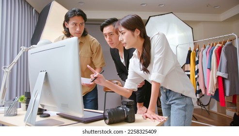 Female Asian photographer reviewing products using computer with crews or client - Powered by Shutterstock