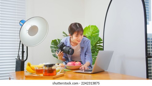 Female Asian photographer taking picture of healthy food checking image with laptop - Powered by Shutterstock