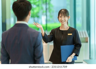 female asian receptionist serving customer in a hotel lobby - Shutterstock ID 2311311709