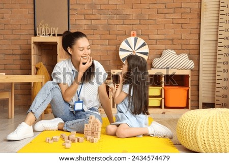 Female Asian speech therapist working with cute little girl in office