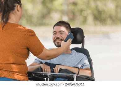 Female assistant helping a man with disability use a smartphone. - Powered by Shutterstock