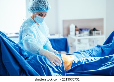 Female Assistant Nurse Preparing The Patient For Surgery. Operation Under General Anesthesia. Modern Surgery Room. Real Photo In Operating Room. Gynecology.