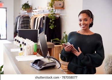 Female Assistant Smiling From The Counter In Clothing Store