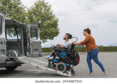 Female assistant transferring a man with disability into the vehicle by pushing his wheelchair up the accessible car ramp. - Powered by Shutterstock