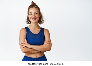 Female athelte in sportswear cross arms on chest. Athletic sportswoman in confident pose smiling at camera, white background. - Powered by Shutterstock