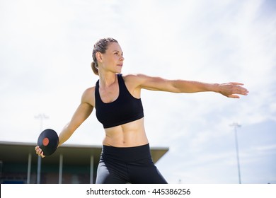 Female athlete about to throw a discus in stadium - Powered by Shutterstock