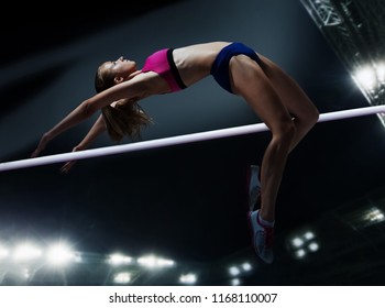 The female athlete in action. high jump over bar at stadium at night - Powered by Shutterstock