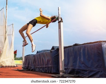 Female Athlete In Action High Jump Over Bar In Track And Field