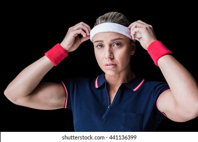 Female athlete adjusting her headband on black background