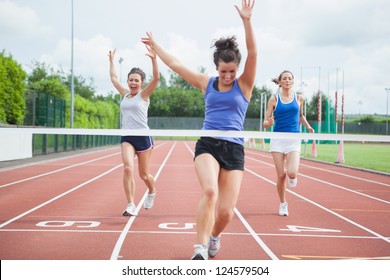 Female athlete celebrates win at finish line at track field - Powered by Shutterstock