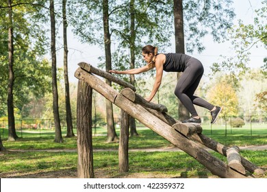 Female athlete crossing wooden obstacle in park - Powered by Shutterstock