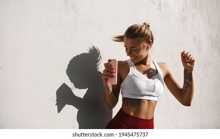 Female Athlete Dancing Outdoors. Sport Woman Dancing With Phone, Listen Music On Run Workout, Runner Having Fun Outside On Fresh Air. Sportswoman Enjoy Fitness Training And Smile