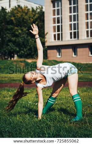 Female athlete does sport exercises in the stadium in a summer day