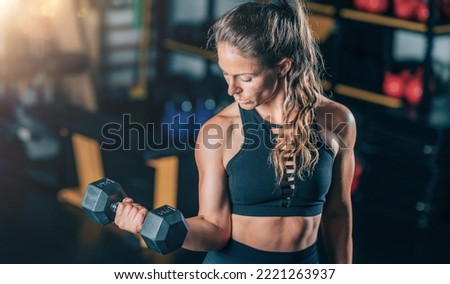 Female Athlete Doing Biceps Exercise with Dumbbells. Strength Training.