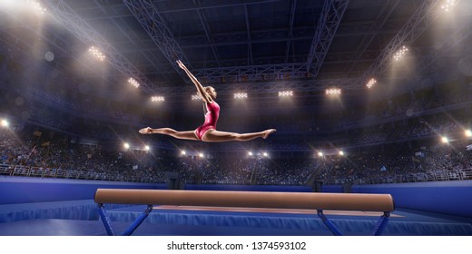 Female Athlete Doing A Complicated Exciting Trick On Gymnastics Balance Beam In A Professional Gym. Girl Perform Stunt In Bright Sports Clothes